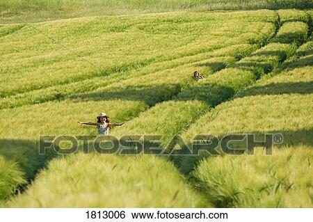 Carefree girls running in sunny, idyllic green rural wheat field View Large Photo Image Stock Photograph - Carefree girls running in sunny, idyllic green rural wheat field. Fotosearch