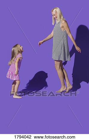 Carefree mother and daughter in striped dresses dancing against purple background View Large Photo Image Stock Image - Carefree mother and daughter in striped dresses dancing against purple background. Fotosearch