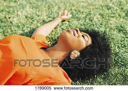 Carefree, serene young woman laying in sunny grass View Large Photo Image Stock Photography - Carefree, serene young woman laying in sunny grass. Fotosearch