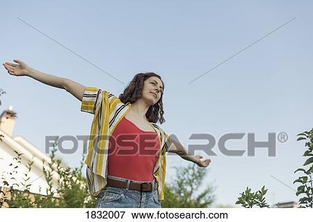 Carefree woman with arms outstretched in back yard View Large Photo Image Stock Photo - Carefree woman with arms outstretched in back yard. Fotosearch