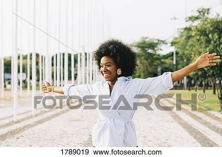 Carefree young woman with arms outstretched in sunny park View Large Photo Image Stock Photo - Carefree young woman with arms outstretched in sunny park. Fotosearch