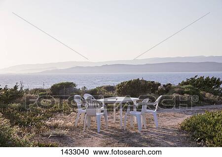 Chairs and table on beach against clear sky View Large Photo Image Stock Image - Chairs and table on beach against clear sky. Fotosearch