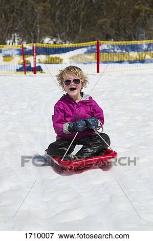Cheerful boy tobogganing on snow covered field View Large Photo Image Stock Photo - Cheerful boy tobogganing on snow covered field. Fotosearch