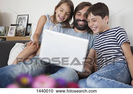 Cheerful father with children using laptop on sofa at home View Large Photo Image Stock Image - Cheerful father with children using laptop on sofa at home. Fotosearch