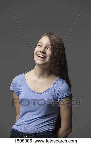 Cheerful girl laughing while standing against gray background View Large Photo Image Stock Photograph - Cheerful girl laughing while standing against gray background. Fotosearch
