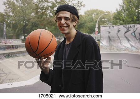 Cheerful young man playing with basketball at park View Large Photo Image Stock Image - Cheerful young man playing with basketball at park. Fotosearch