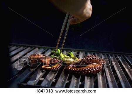 Chef with chopsticks grilling octopus View Large Photo Image Stock Photo - Chef with chopsticks grilling octopus. Fotosearch