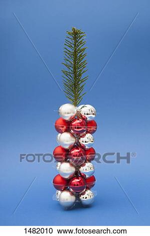 Stock Image - Christmas tree made of twig and ornaments against blue background. Fotosearch