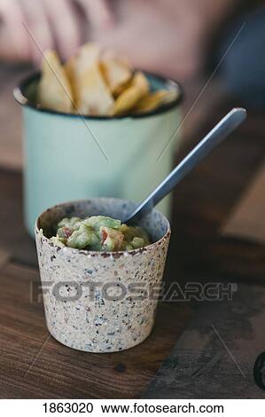Stock Image - Close up fresh, homemade tortilla chips and guacamole. Fotosearch