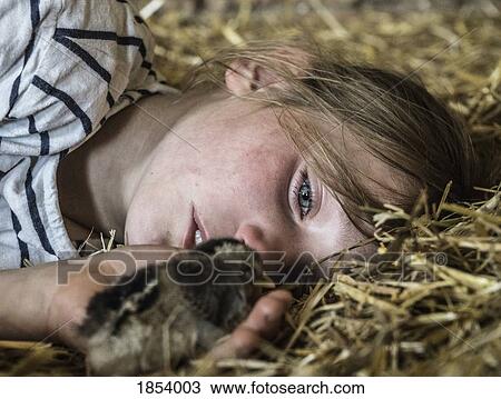Stock Image - Close up girl holding baby chick in straw. Fotosearch