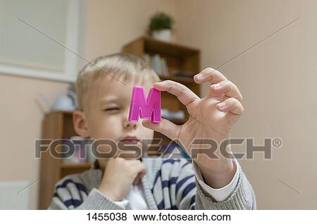 Stock Photo - Close-up of boy holding letter M. Fotosearch