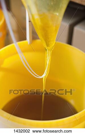 Stock Image - Close-up of fresh honey being poured in container. Fotosearch