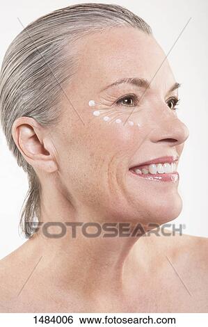 Close-up of happy mature woman with dots of moisturizing cream on face against white background View Large Photo Image Stock Photograph - Close-up of happy mature woman with dots of moisturizing cream on face against white background. Fotosearch