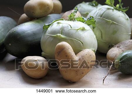Stock Image - Close-up of heart shape potato with vegetables on table. Fotosearch