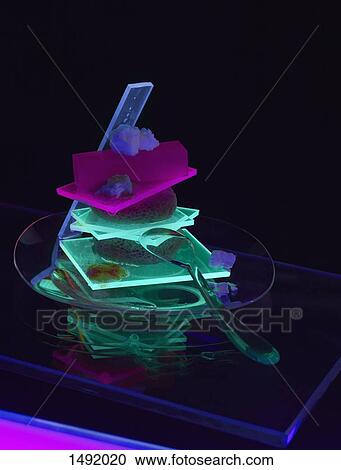 Stock Image - Close-up of illuminated food served on table against black background. Fotosearch