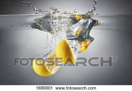 Stock Image - Close-up of lemon slices in splashing water. Fotosearch