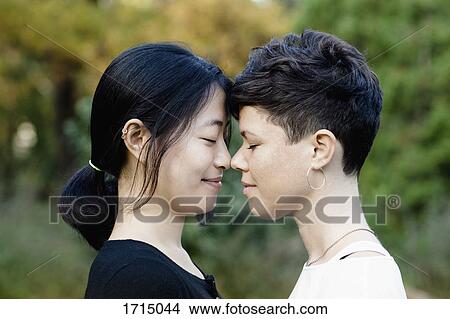 Close-up of smiling lesbian couple standing face to face at park View Large Photo Image Picture - Close-up of smiling lesbian couple standing face to face at park. Fotosearch