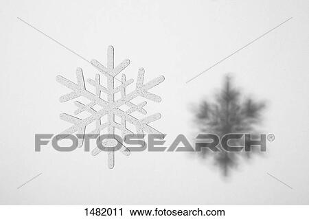 Stock Image - Close-up of snowflake and its shadow against white background. Fotosearch