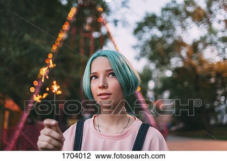 Stock Image - Close-up of teenage girl holding illuminated sparkler. Fotosearch