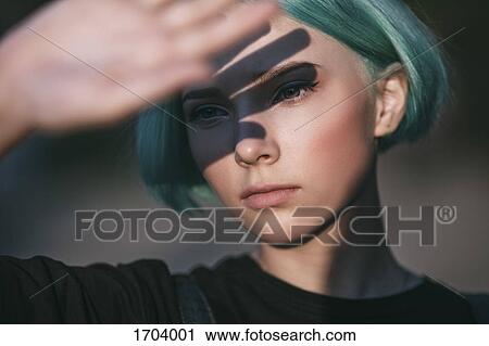 Stock Image - Close-up of teenage girl shielding eyes on sunny day. Fotosearch
