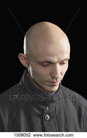 Stock Image - Close-up of thoughtful man against black background. Fotosearch