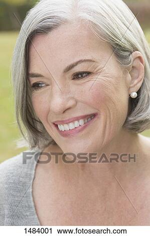 Close-up of thoughtful mature woman smiling while looking away outdoors View Large Photo Image Stock Image - Close-up of thoughtful mature woman smiling while looking away outdoors. Fotosearch