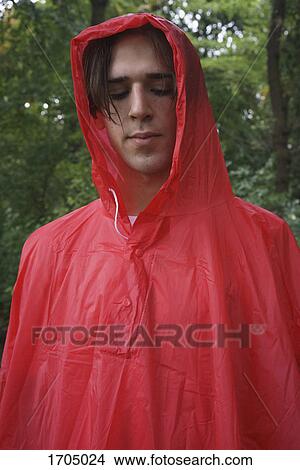 Picture - Close-up of young man wearing red raincoat at park. Fotosearch