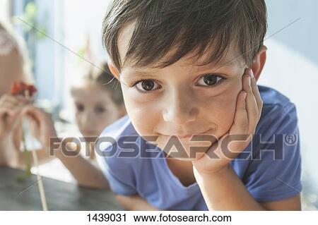 Stock Image - Close-up portrait of cute boy leaning on table at home. Fotosearch