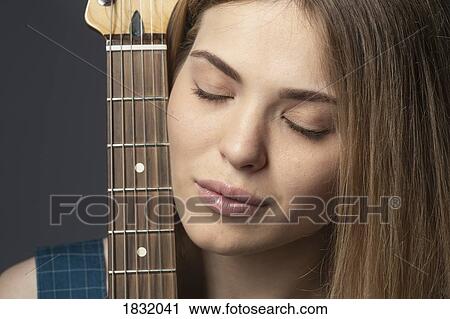 Close up portrait serene young woman with guitar View Large Photo Image Stock Image - Close up portrait serene young woman with guitar. Fotosearch