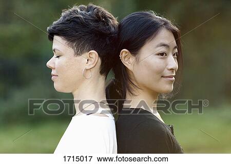 Close-up side view of friends standing back to back at park View Large Photo Image Stock Photo - Close-up side view of friends standing back to back at park. Fotosearch