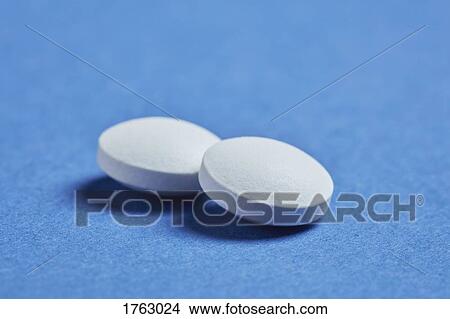 Picture - Close up two pills on blue background. Fotosearch