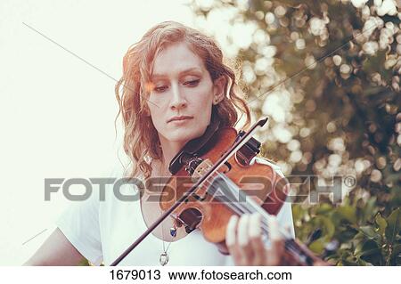 Confident beautiful woman playing violin against plants View Large Photo Image Stock Image - Confident beautiful woman playing violin against plants. Fotosearch