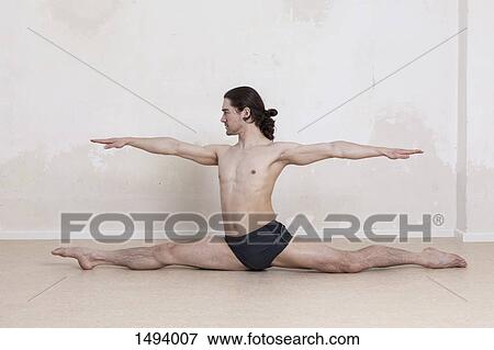 Confident man with arms outstretched doing splits while performing yoga View Large Photo Image Stock Photo - Confident man with arms outstretched doing splits while performing yoga. Fotosearch