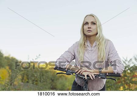 Confident, serious woman riding bicycle in park View Large Photo Image Stock Photograph - Confident, serious woman riding bicycle in park. Fotosearch