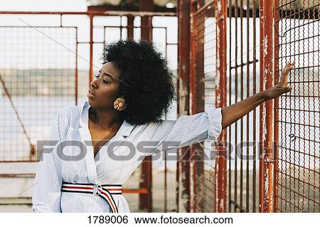 Confident young woman leaning on gate View Large Photo Image Stock Photograph - Confident young woman leaning on gate. Fotosearch