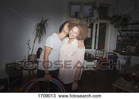 Couple embracing while standing against wall at home View Large Photo Image Stock Image - Couple embracing while standing against wall at home. Fotosearch