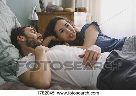 Stock Photography - Couple relaxing and talking on bed. Fotosearch