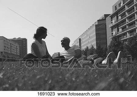 Couple resting on grassy field against clear sky in city View Large Photo Image Stock Image - Couple resting on grassy field against clear sky in city. Fotosearch