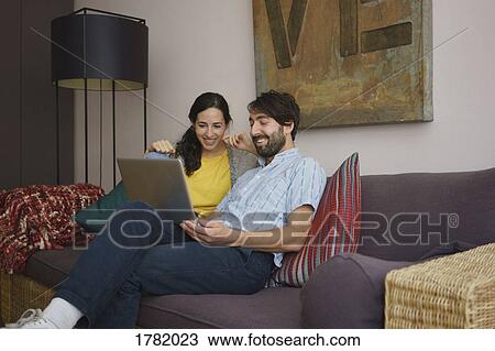 Couple using laptop on living room sofa View Large Photo Image Stock Image - Couple using laptop on living room sofa. Fotosearch
