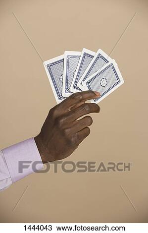Cropped hand holding playing cards against colored background View Large Photo Image Stock Image - Cropped hand holding playing cards against colored background. Fotosearch