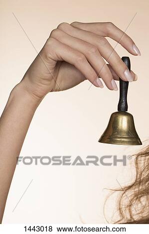 Cropped hand of woman holding bell against colored background View Large Photo Image Stock Photo - Cropped hand of woman holding bell against colored background. Fotosearch