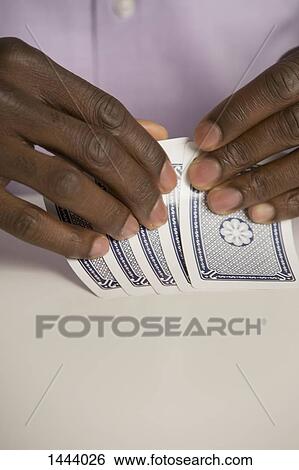 Stock Photograph - Cropped hands holding cards at table. Fotosearch