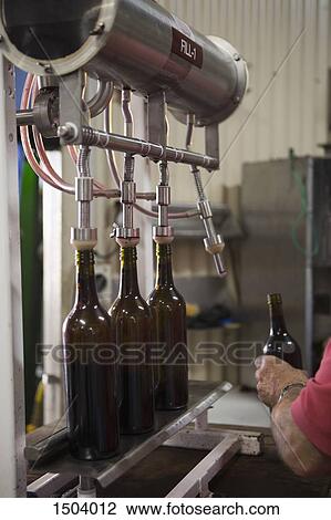 Stock Image - Cropped image of a man holding bottle in a factory. Fotosearch