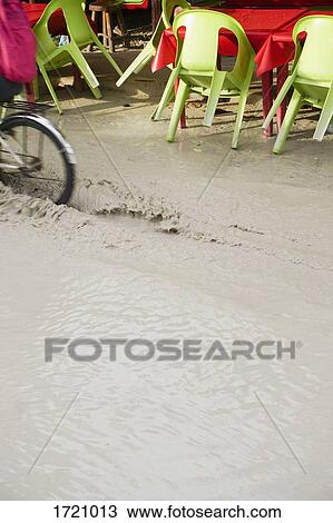 Cropped image of bicycle moving through dirty water by sidewalk cafe View Large Photo Image Stock Image - Cropped image of bicycle moving through dirty water by sidewalk cafe. Fotosearch
