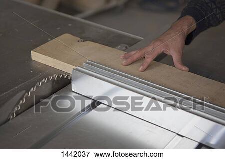Stock Photo - Cropped image of carpenter using sliding table saw in workshop. Fotosearch