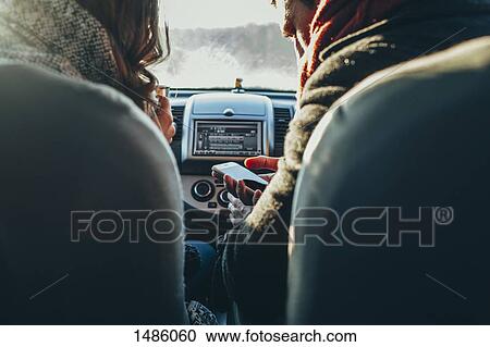 Cropped image of couple using smart phone in car View Large Photo Image Stock Image - Cropped image of couple using smart phone in car. Fotosearch