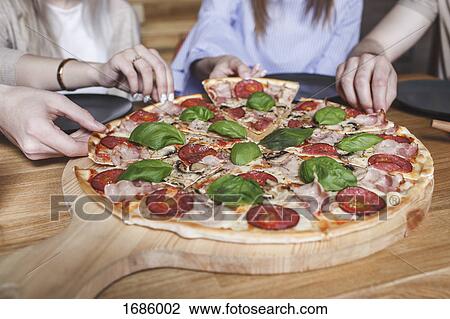 Cropped image of friends having pizza at restaurant View Large Photo Image Stock Image - Cropped image of friends having pizza at restaurant. Fotosearch