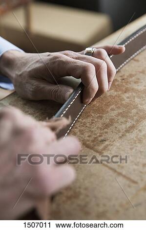 Cropped image of hand holding belt on table View Large Photo Image Stock Image - Cropped image of hand holding belt on table. Fotosearch