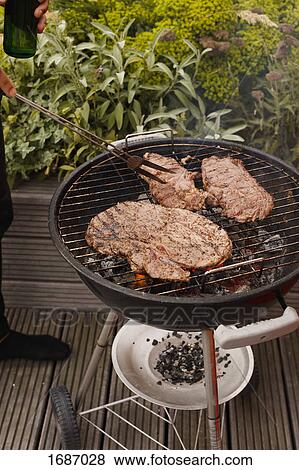 Cropped image of man cooking steak on barbecue grill on patio View Large Photo Image Stock Photo - Cropped image of man cooking steak on barbecue grill on patio. Fotosearch