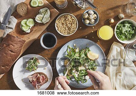 Stock Photo - Cropped image of man mixing salad with fork and table knife in plate on table. Fotosearch